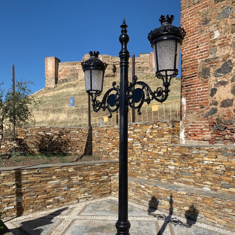 Farola Villa de hierro fundido instalada en entorno histórico con castillo al fondo