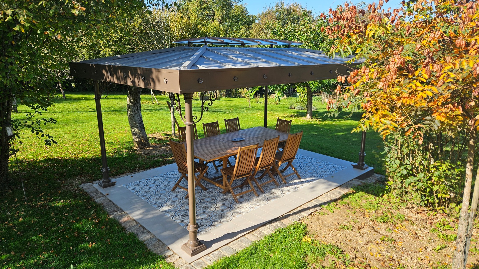 Pérgola exterior en jardín con columnas de hierro fundido y cubierta clásica